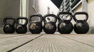Kettlebells lined up on deck from smallest to biggest https://get-strong.fit/Fitness